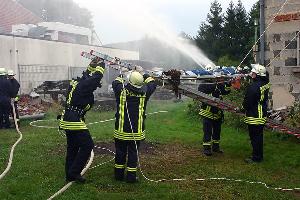 Bild: Mittels eines Leiterhebels wird eine Person aus dem brennenden Geb&amp;auml;ude gerettet