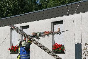 Bild: Eine Person wird mit einem sogenannten Leiterhebel vom Dach des Geb&amp;auml;udes gerettet
