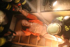 Bild: Eine &amp;Uuml;bungspuppe wird von Feuerwehrleuten aus einem Keller gerettet