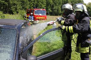 Bild: Ein mit schwerem Atemschutz ausgestatteter Trupp bek&amp;auml;mpft den Fahrzeugbrand mit dem Schnellangriff und einem Schaumrohr