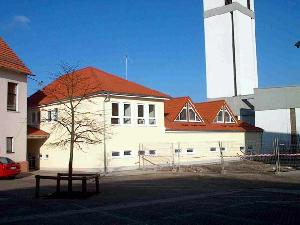 Bild: hintere Teilansicht des Ger&amp;auml;tehauses vom Schulhof (im Hintergrund: die kath. Pfarrkirche Wiesbach)