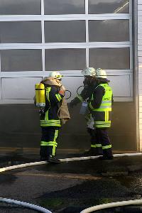Bild: Besprechung vor der brennenden Werkshalle - Noch immer tritt Rauch aus
