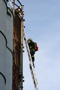 Bild: Ein Rettungssanit&amp;auml;ter der Feuerwehr kletter mit dem Rettungsrucksack auf eines der Silos, um einen Verletzten zu versorgen