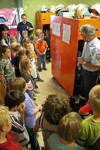 Bild: Löschbezirksführer Felix Becker mit den Grundschülern in der Umkleide mit den Einsatzuniformen