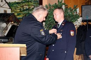 Bild: Kreisbrandinspekteur Werner Thom ehrt den Oberl&amp;ouml;schmeister Heiko Bock f&amp;uuml;r 25 Jahre Dienst in der Feuerwehr, mit dem silbernen Ehrenzeichen am Bandes des Saarlandes. (Foto: Heike Blum)