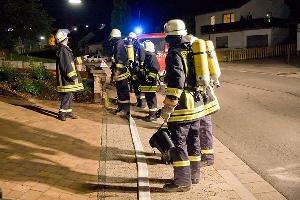 Bild: Mit Atemschutzgeräten ausgerüstete Einsatzkräfte vor dem Anwesen in der Hauptstraße