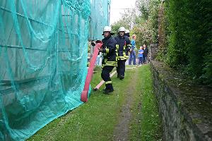 Bild: Verlegen einer B-Schlauchleitung zum Einsatzort hinter der Kirche